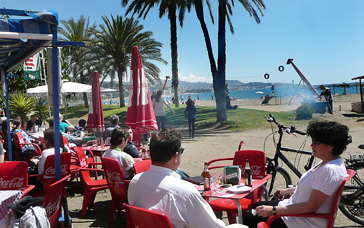 Malaga Spain. Beach Eats Smoke drifts from a fire roasting sardines at a beach Chiringuito